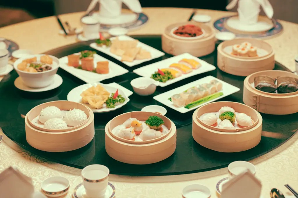 High-angle overhead shot of a lazy Susan filled with bamboo steamers and shared dim sum plates, illustrating communal dining and unspoken food-sharing rituals in yum cha culture.