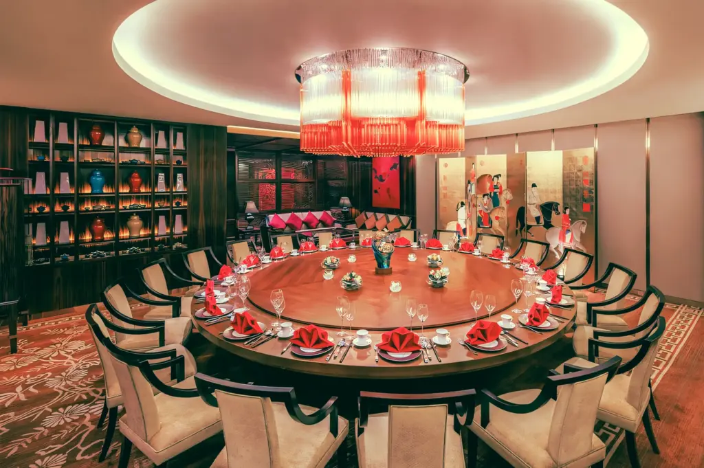 Elegant private dining room with large round table, luxury Chinese restaurant setting, red napkins and chandelier lighting – wide-angle interior shot