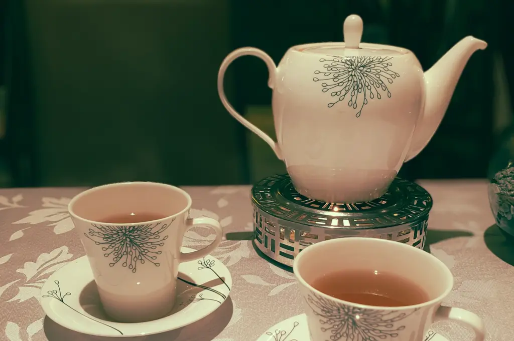 Traditional Chinese tea set with porcelain teapot and cups on table, elegant tea service setup – close-up shot with shallow depth of field